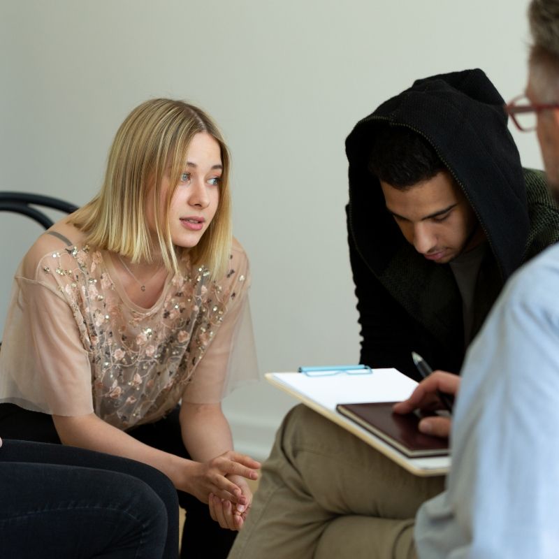 Young man and woman looking at counselor in support group